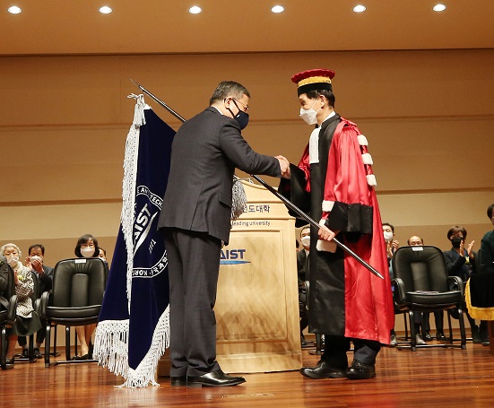 The 16th President Sung-Chul Shin (left) hands over the KAIST flag to his successor President Lee.